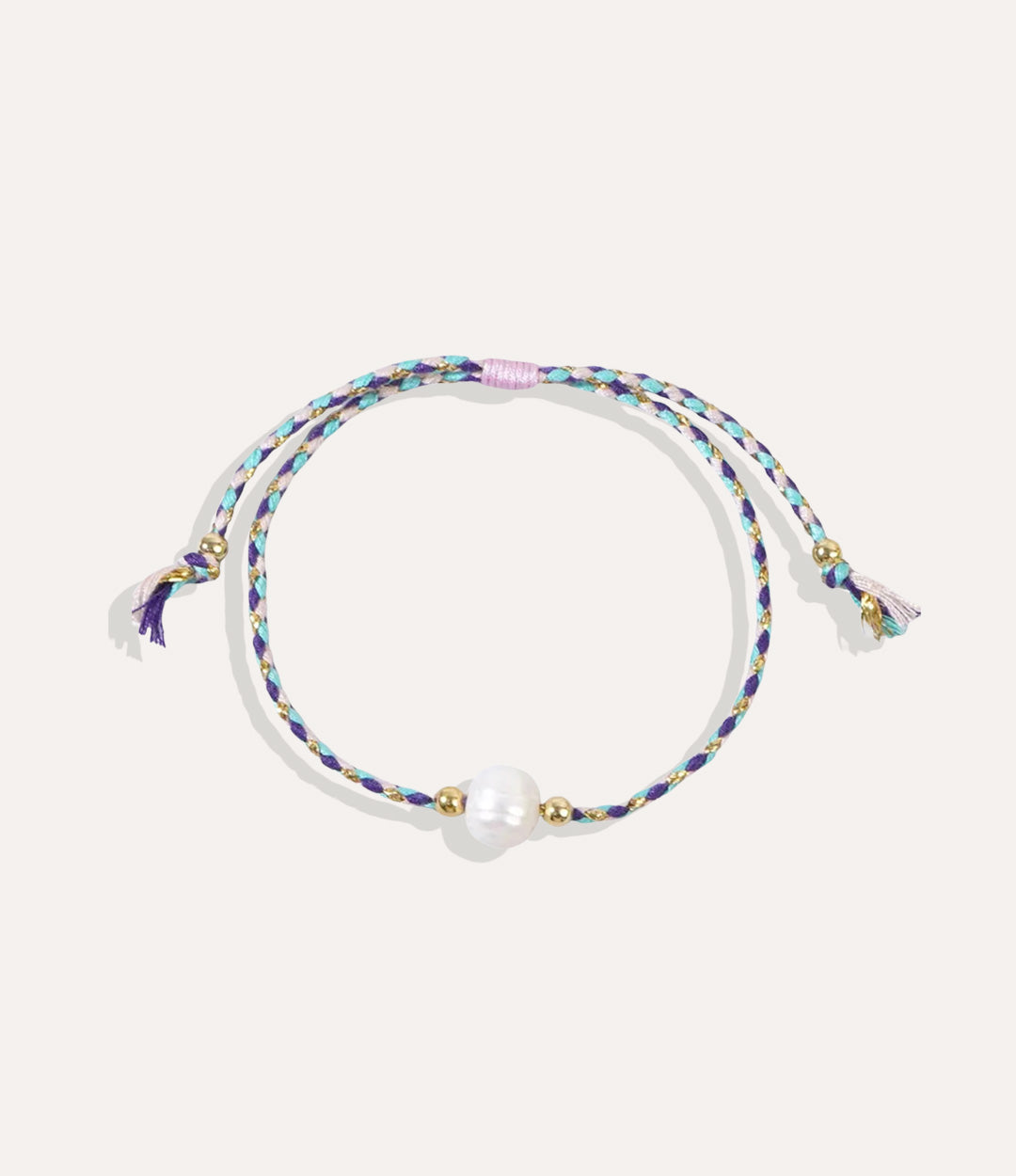 Pearl on a purple string bracelet displayed on a neutral background showcasing its vibrant cord and glossy pearl.