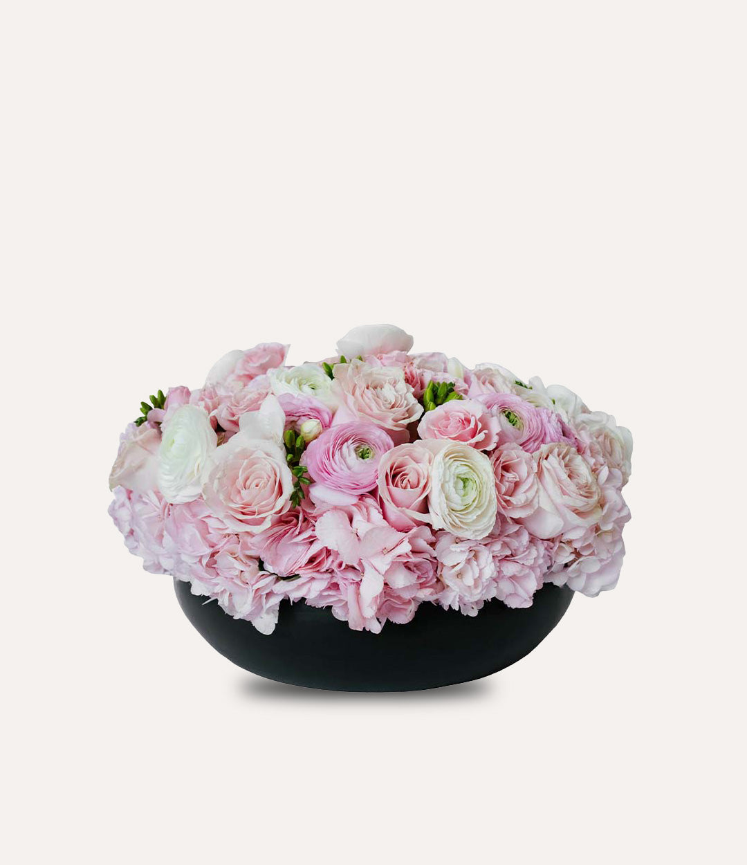 Bouquet of pink and white flowers in a black bowl on a light gray background