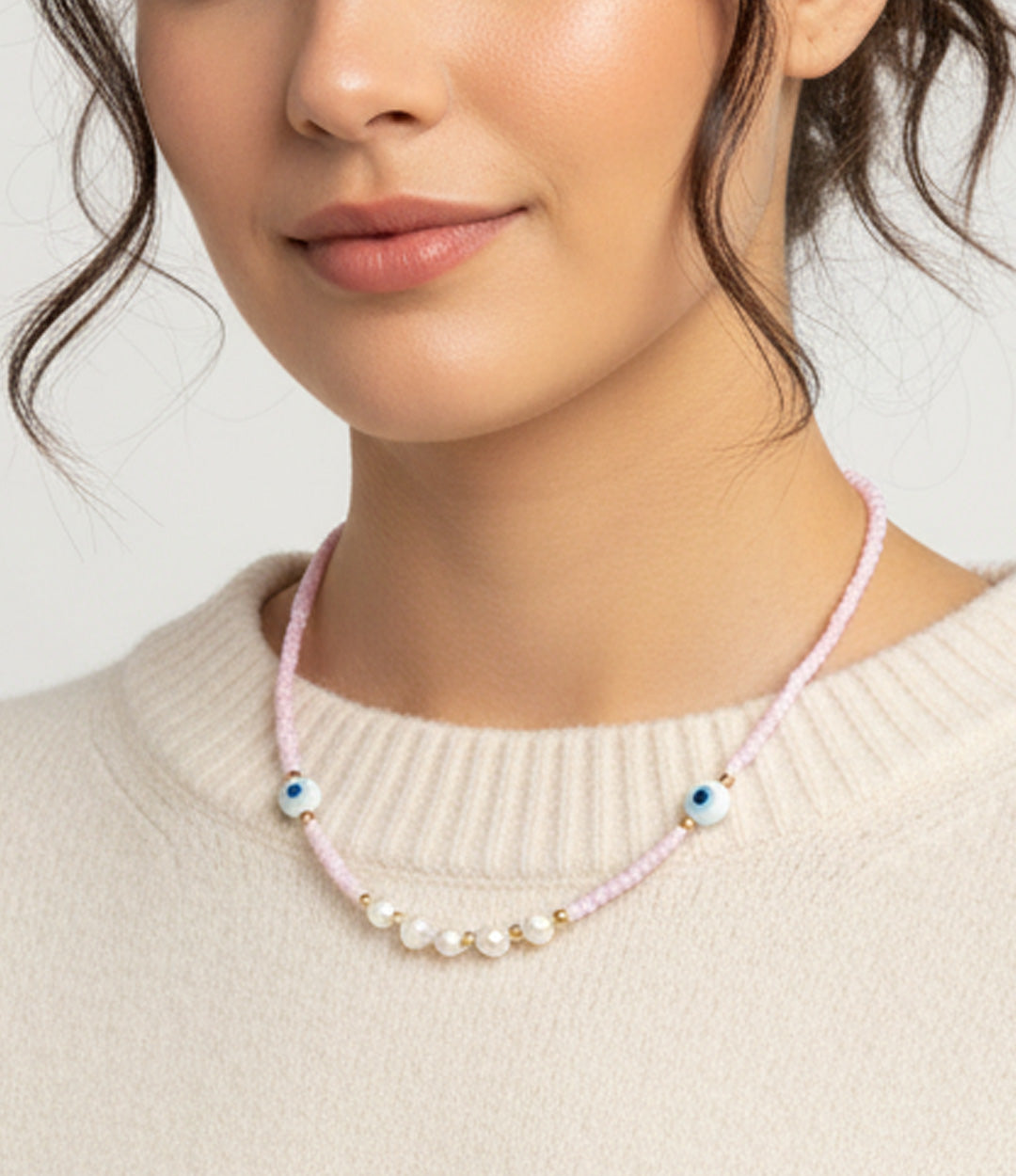 Pink Protection Necklace featuring pink beads, pearls, and blue evil eye charms on model.