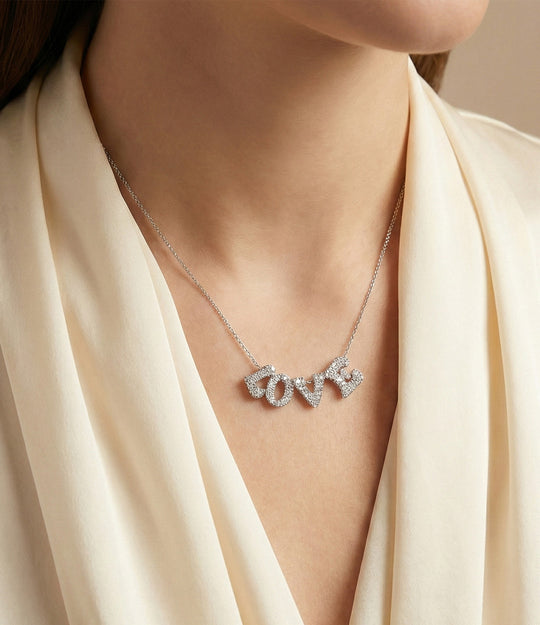 Necklace with 'LOVE' pendant on a person wearing a beige garment