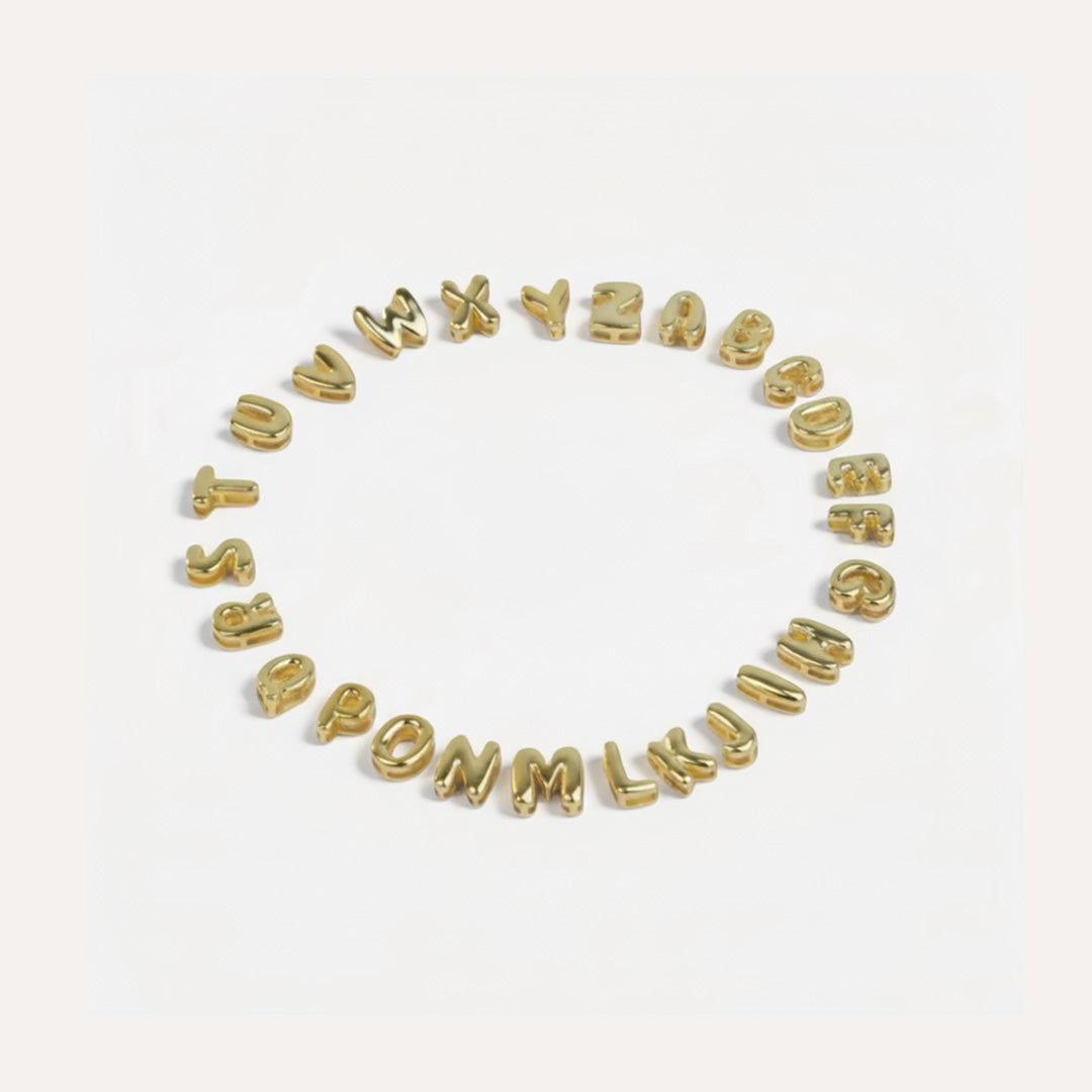 Gold letter beads spelling out the alphabet on a white background