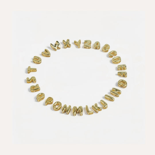 Gold letter beads spelling out the alphabet on a white background