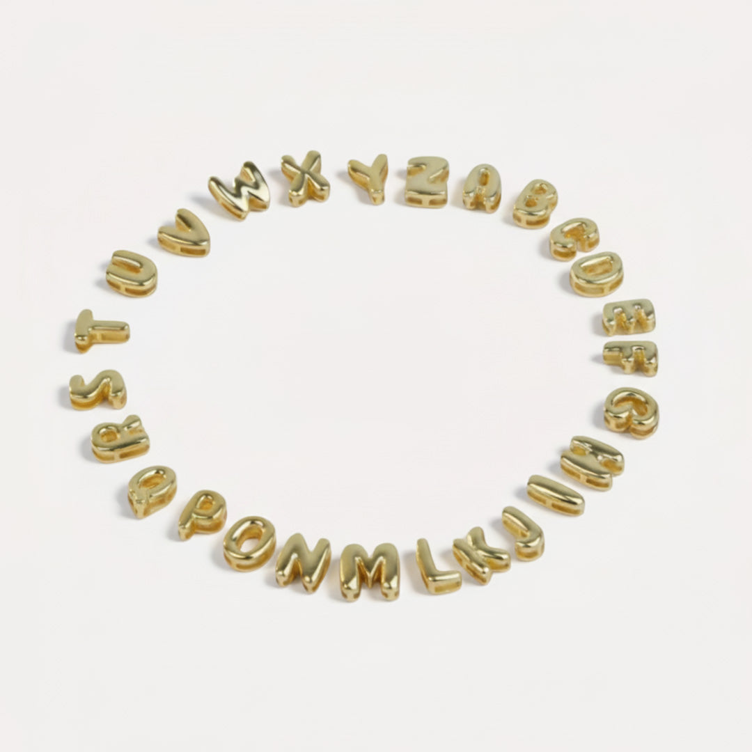 Gold letter beads spelling out the alphabet on a white background