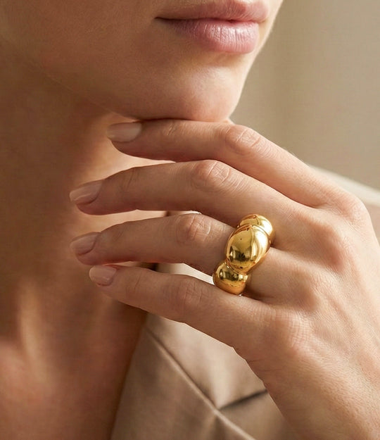Close-up of a hand wearing a gold ring with a blurred background