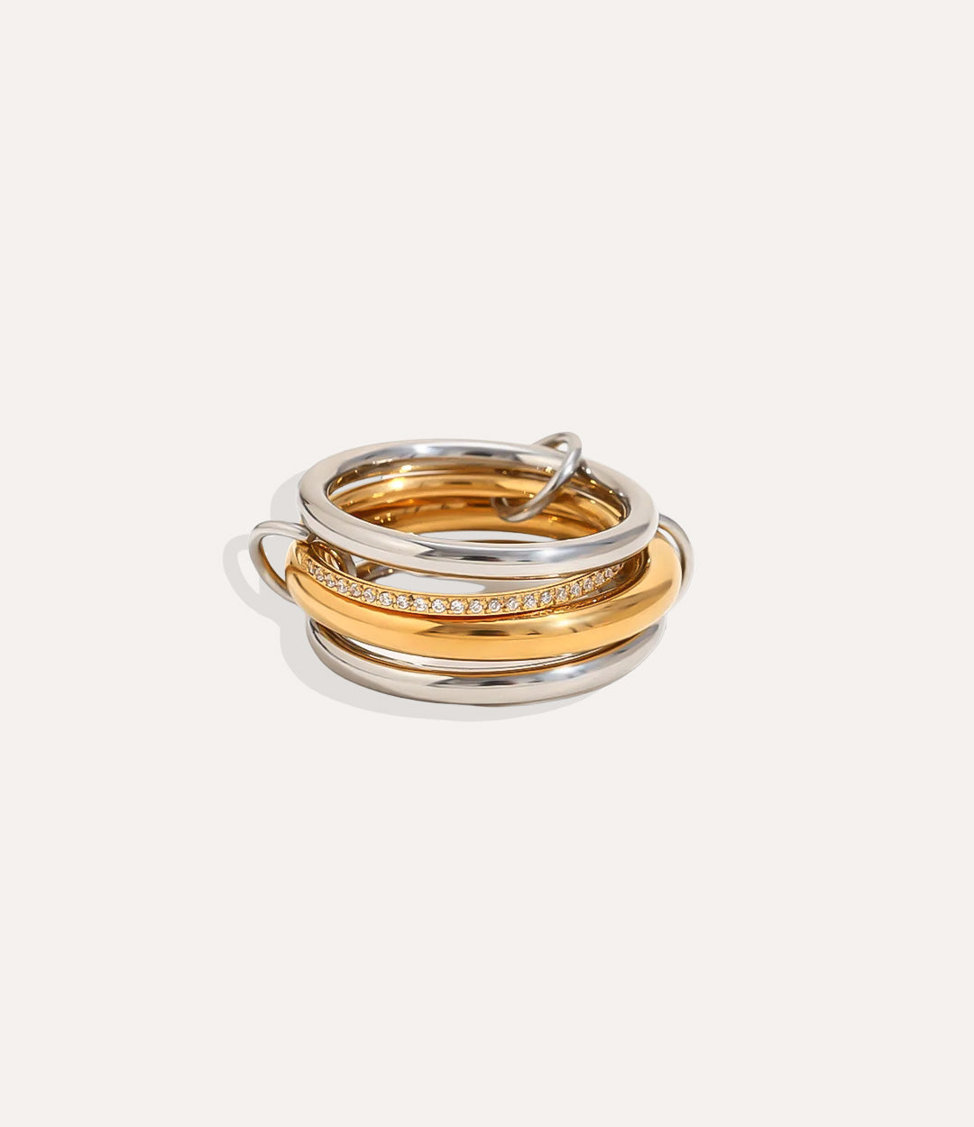 Three gold and silver rings stacked on a light beige background