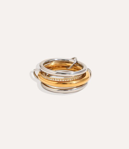 Three gold and silver rings stacked on a light beige background