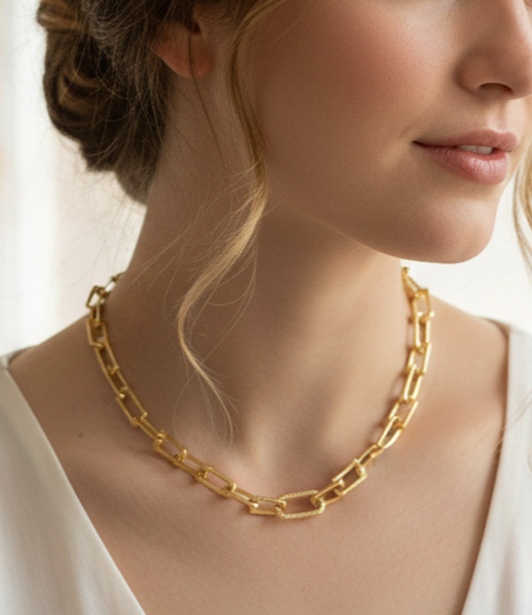Woman wearing a gold chain necklace with a blurred background. Skye Flowers