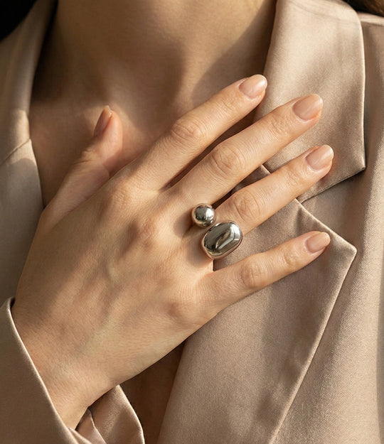 Hand wearing a silver ring on beige fabric