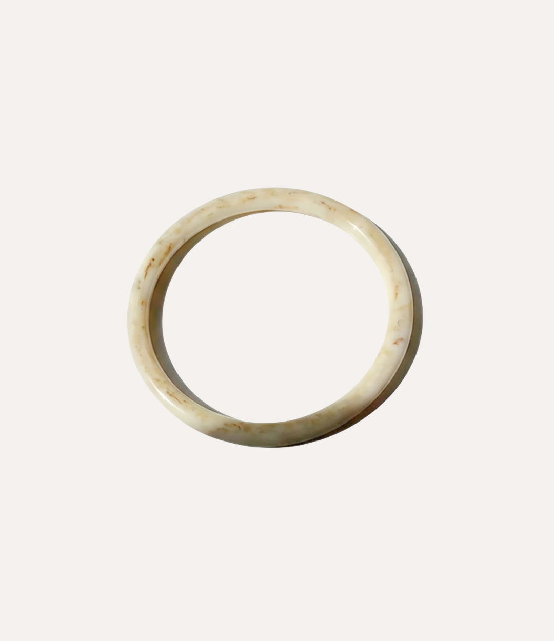 Close-up of a polished round bangle with a smooth, minimalist design on a neutral background