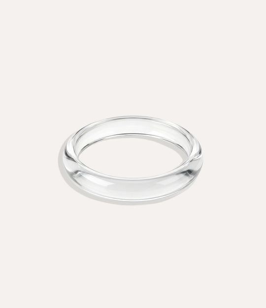 Close-up of a polished clear round bangle with a smooth, minimalist design on a neutral background.