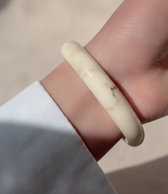 Model wearing a single round bangle to highlight its bold, versatile look.