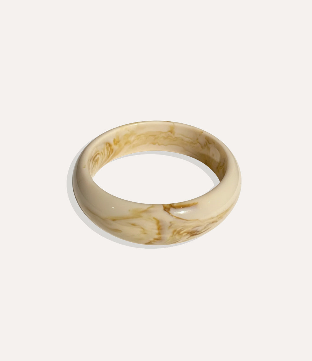 Close-up of a polished round bangle with a smooth, minimalist design on a neutral background.