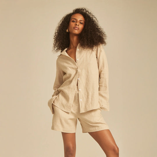 Woman wearing a beige shirt and shorts set against a plain background