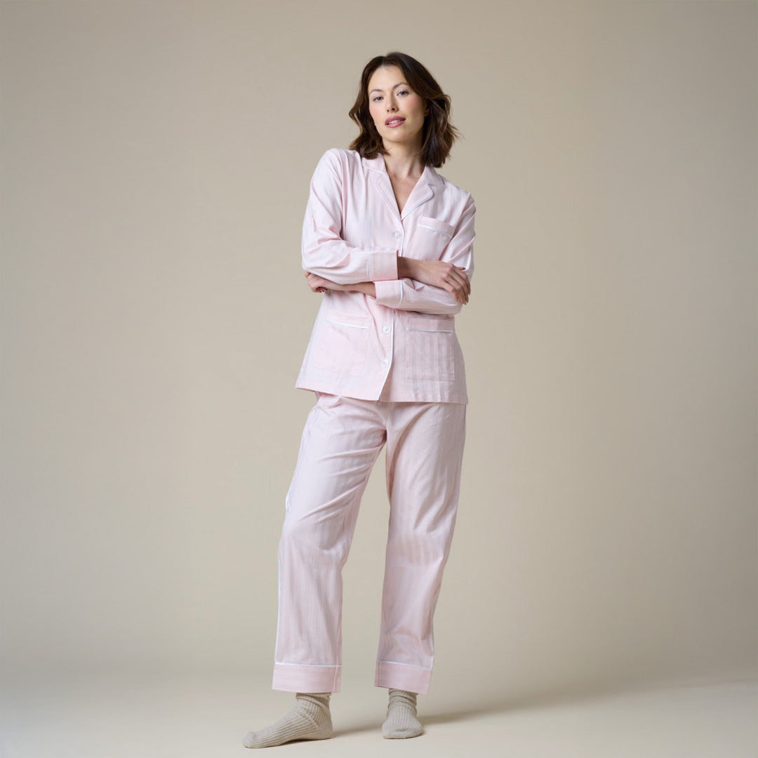 Woman wearing a light pink pajama set against a beige background
