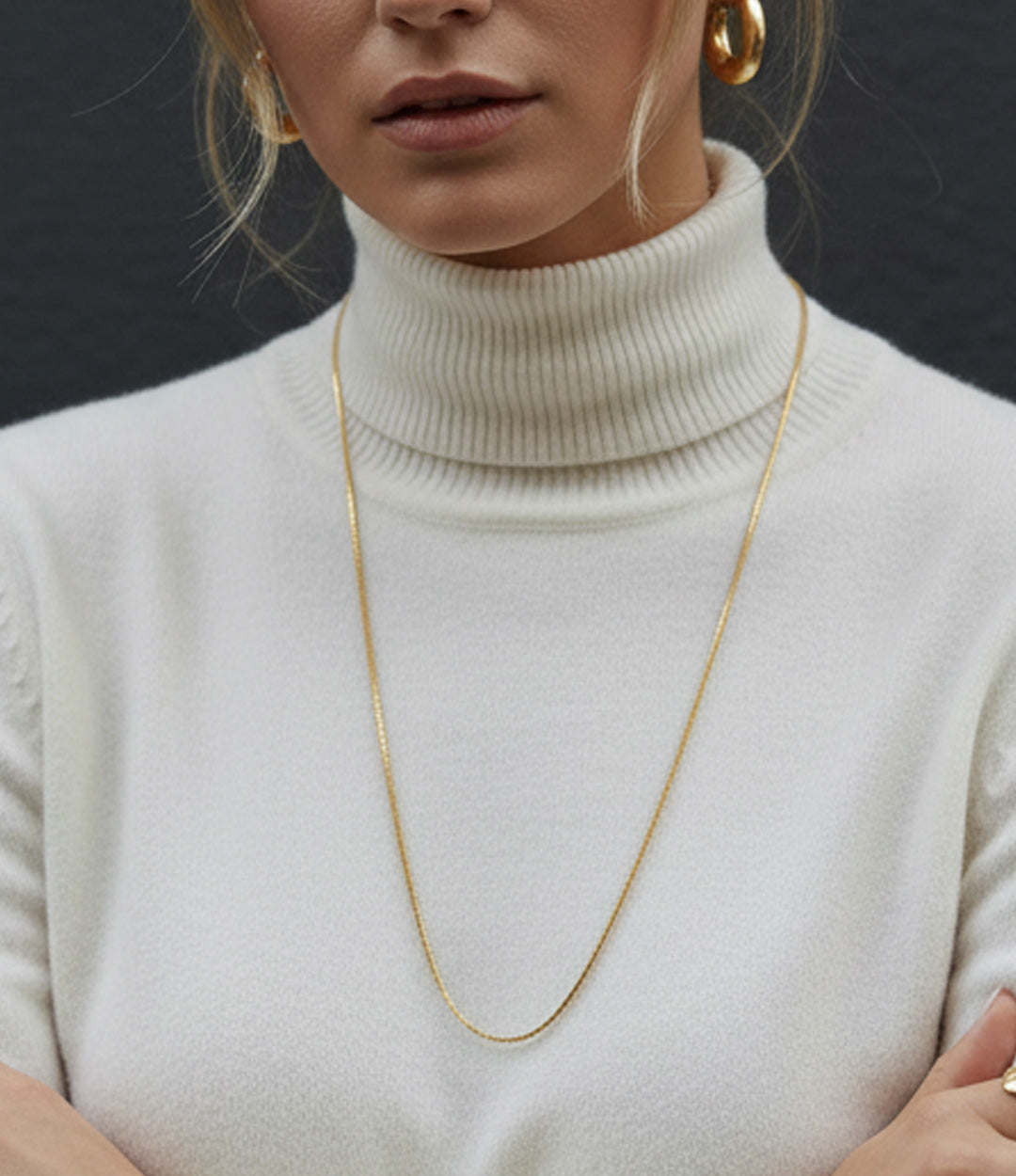 Person wearing a gold necklace with a plain background