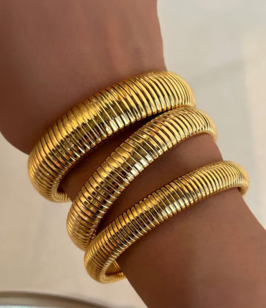 Model wearing the Snake Stretch Bangle in different sizes, showing their bold, chunky, snake-inspired stretch design.