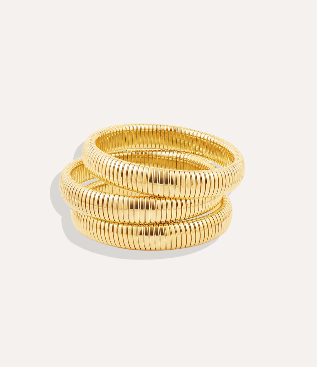Set of gold bangles on a light gray background
