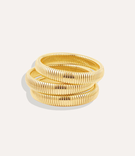 Set of gold bangles on a light gray background