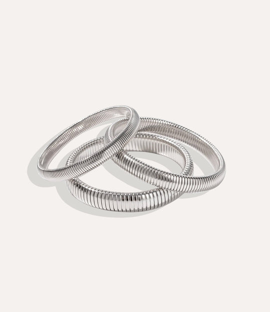 Set of silver bangles on a light gray background