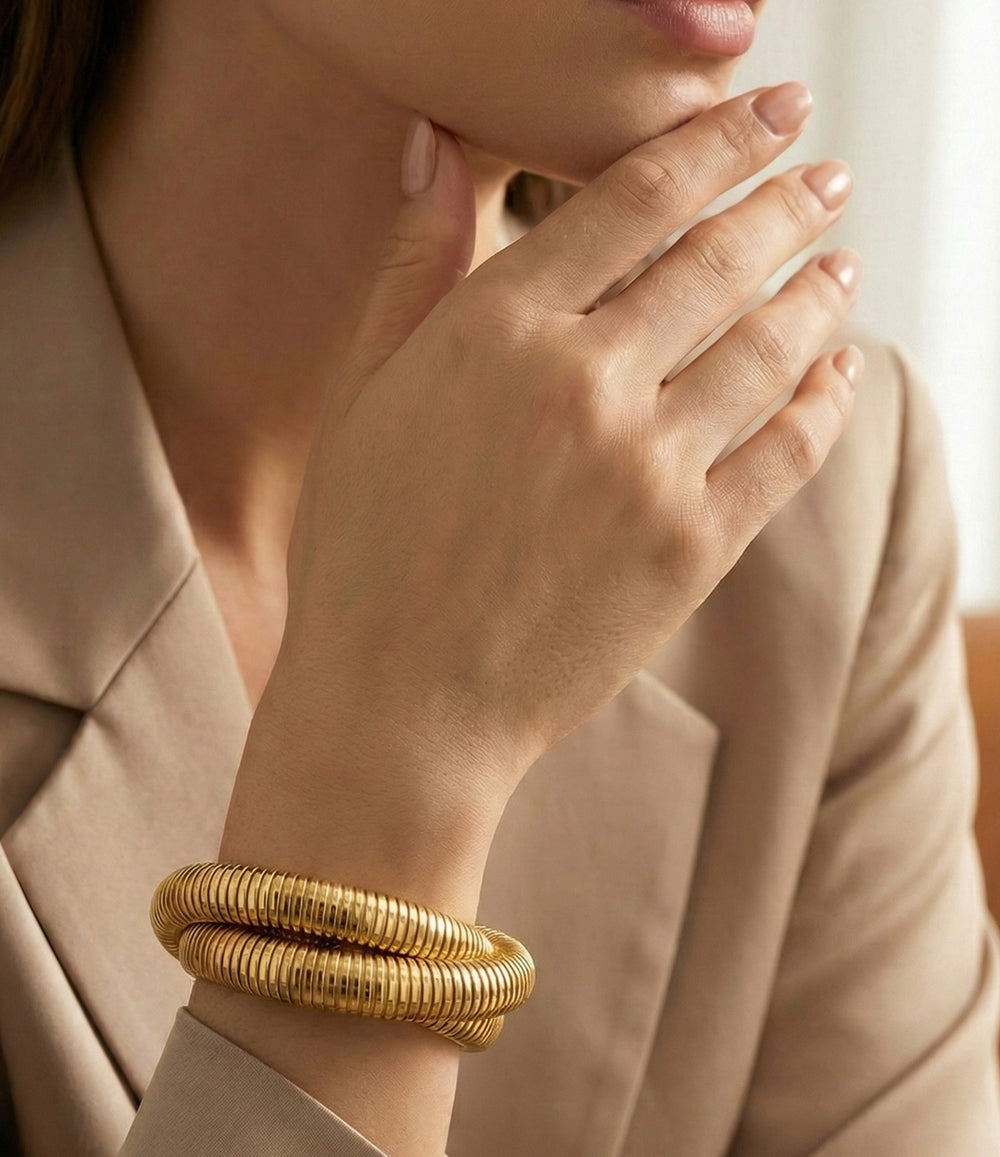 Gold bracelet on a person's wrist with a neutral background