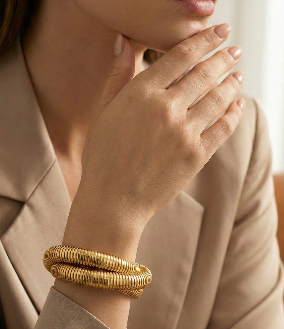 Gold bracelet on a person's wrist with a neutral background