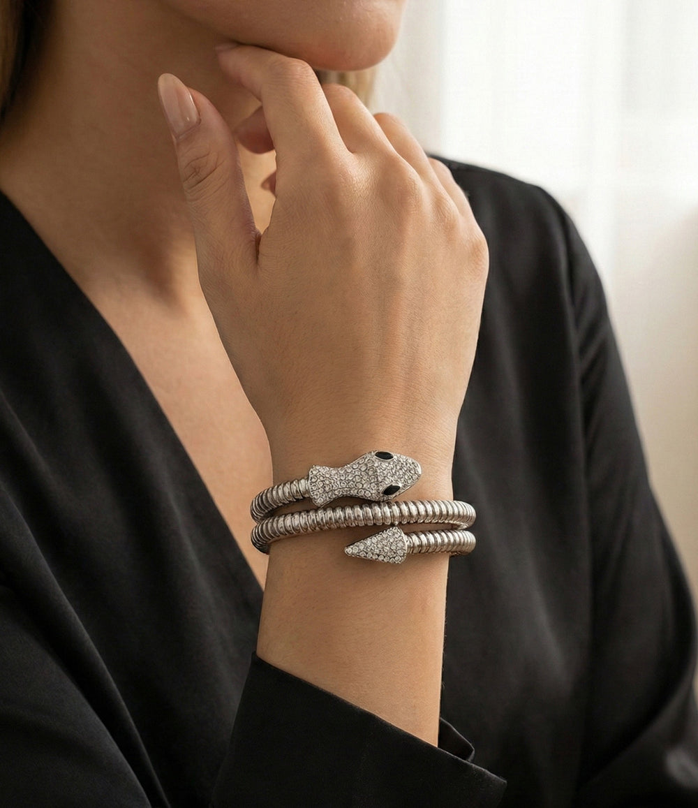 Close-up of a hand wearing multiple silver bracelets with a blurred background