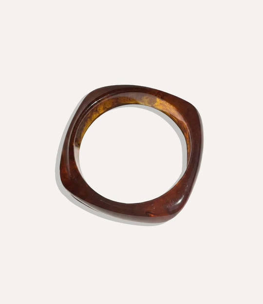 Chunky square bangle made of acrylic and resin in brown colour displayed on a neutral background.
