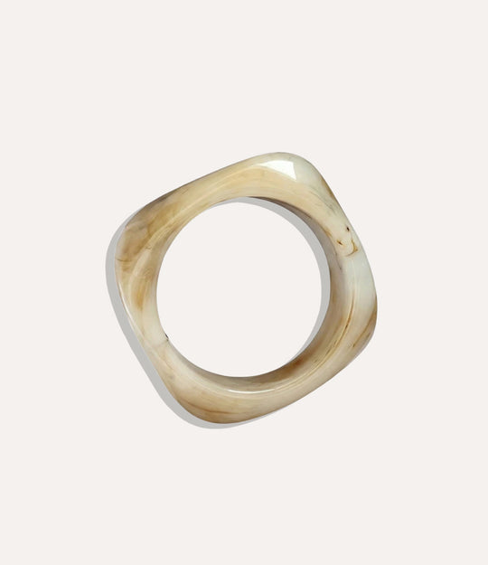 Chunky square bangle made of acrylic and resin in ivory colour displayed on a neutral background.