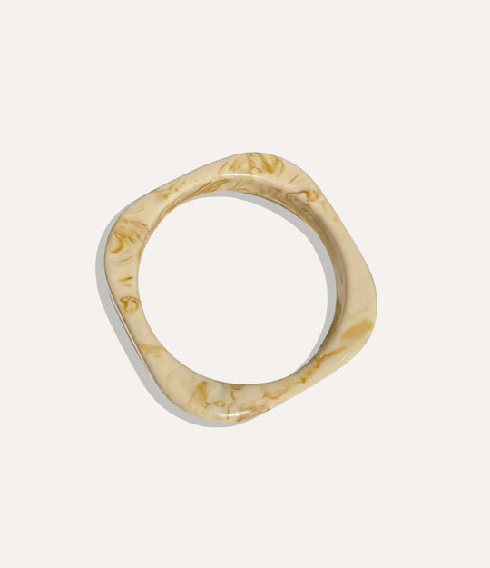 Chunky square bangle made of acrylic and resin in tan colour displayed on a neutral background.