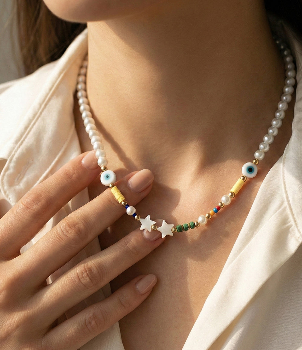 Pearl necklace with colorful beads and star charms worn by a person.