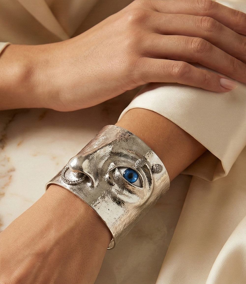 Close-up of the Statement Eye Cuff showing detailed face motif and polished metal finish.