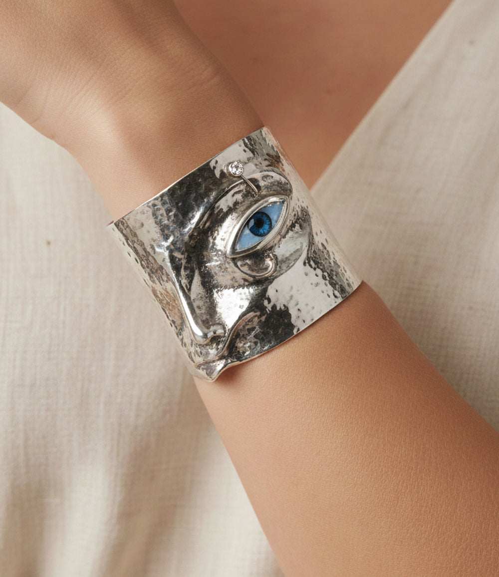 Close-up of the Statement Eye Cuff showing detailed face motif and polished metal finish.