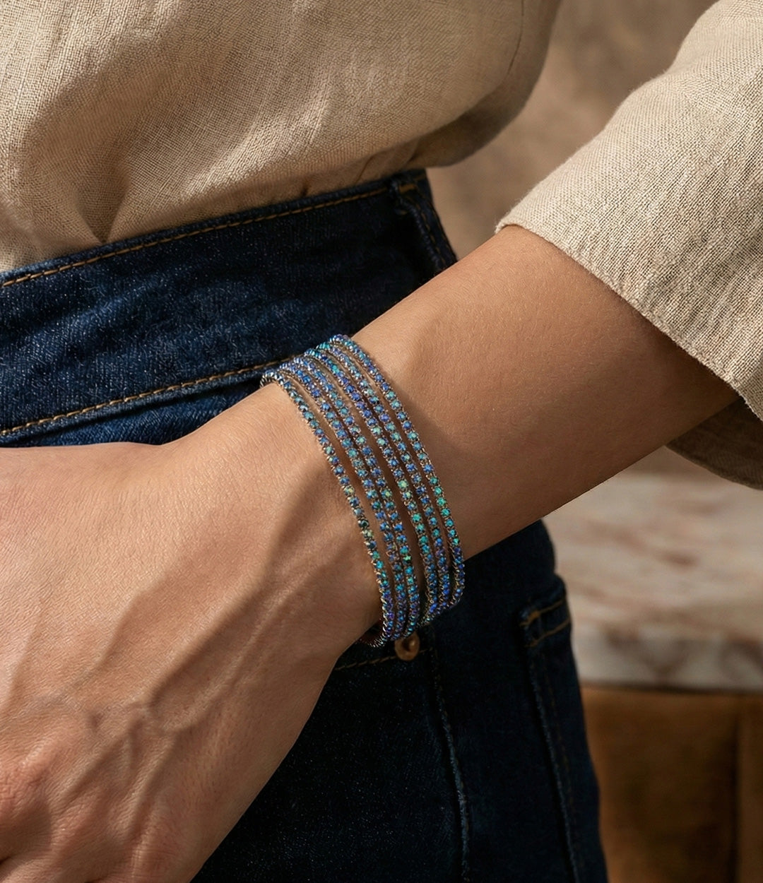 Person wearing multiple beaded bracelets on a neutral background