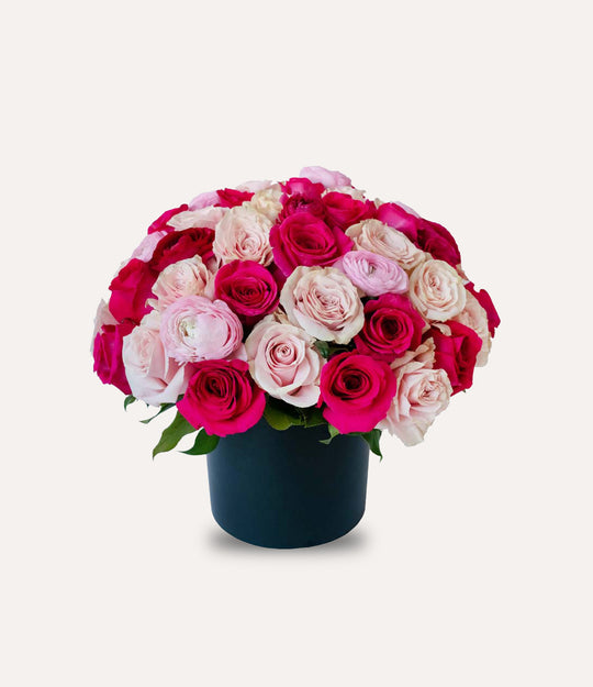Bouquet of pink and white roses in a navy vase on a light gray background
