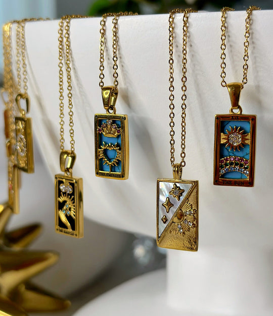 Close-up of 14K gold-plated tarot card necklaces showing engraved card details.