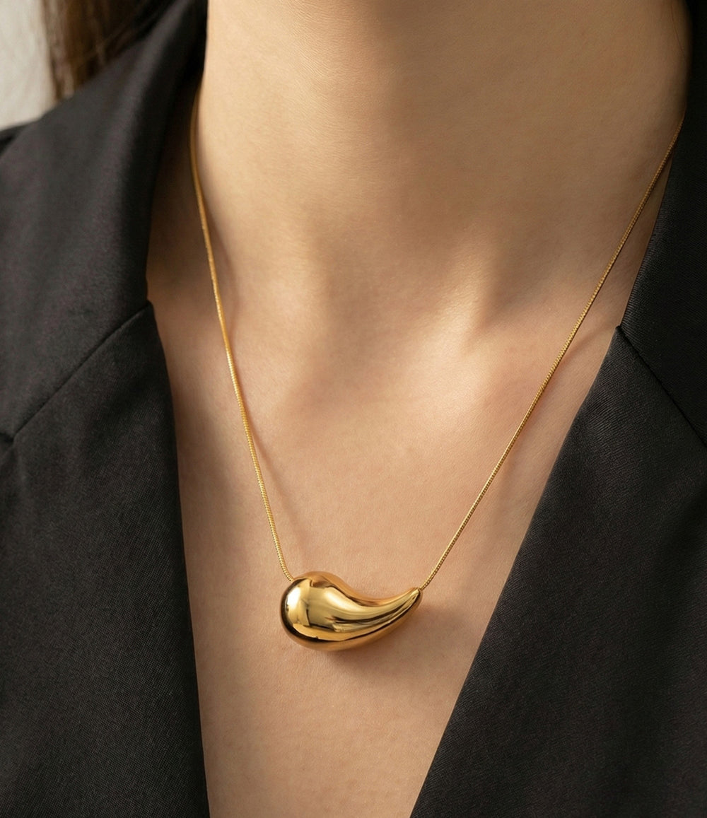 Woman wearing a necklace with a tear drop charm.