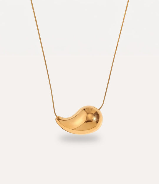 Close-up of the teardrop pendant showcasing its polished gold finish.