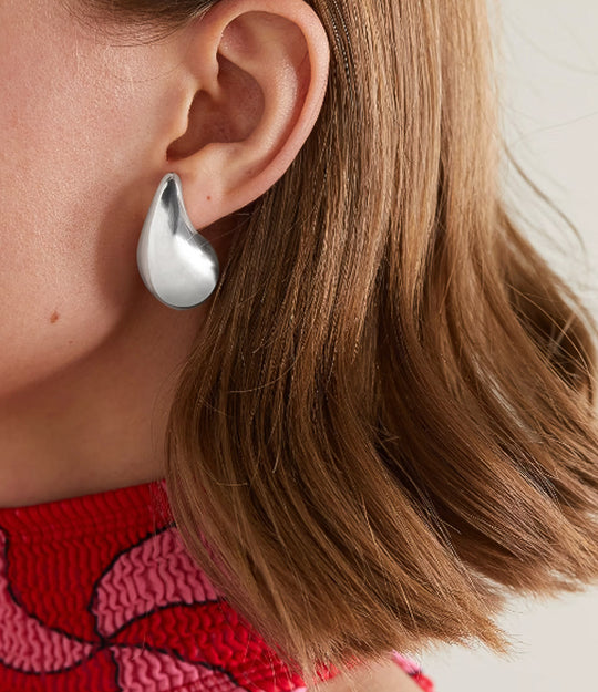 Close up of a model wearing the Tear Drop Stud in silver showing the trendy puffy shape and elegant sculptural fit against a neutral background.