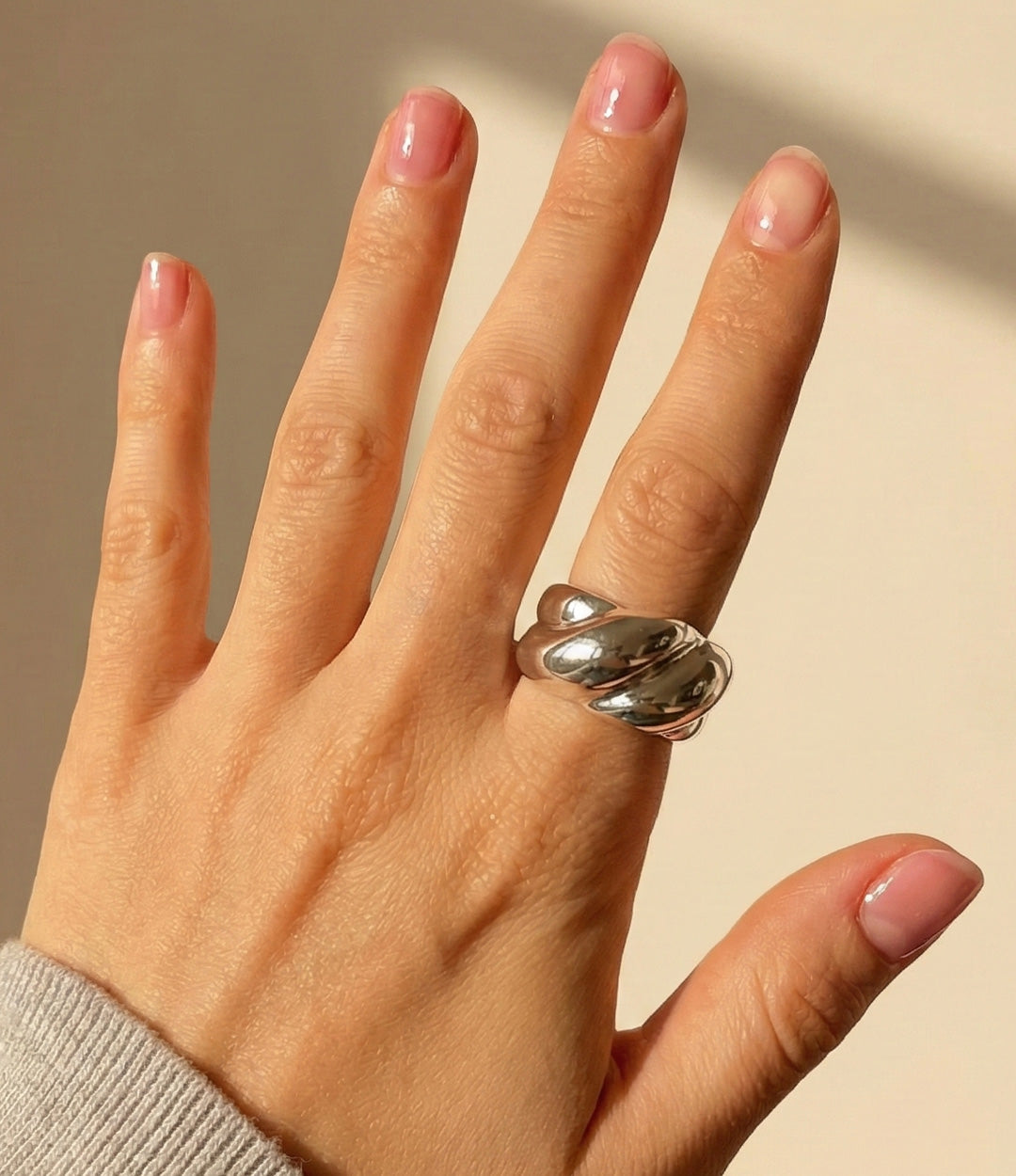 Model wearing The Big Twist Ring in 18k gold plated finish and silver, featuring a thick rope-style twisted band design, isolated on a plain background.