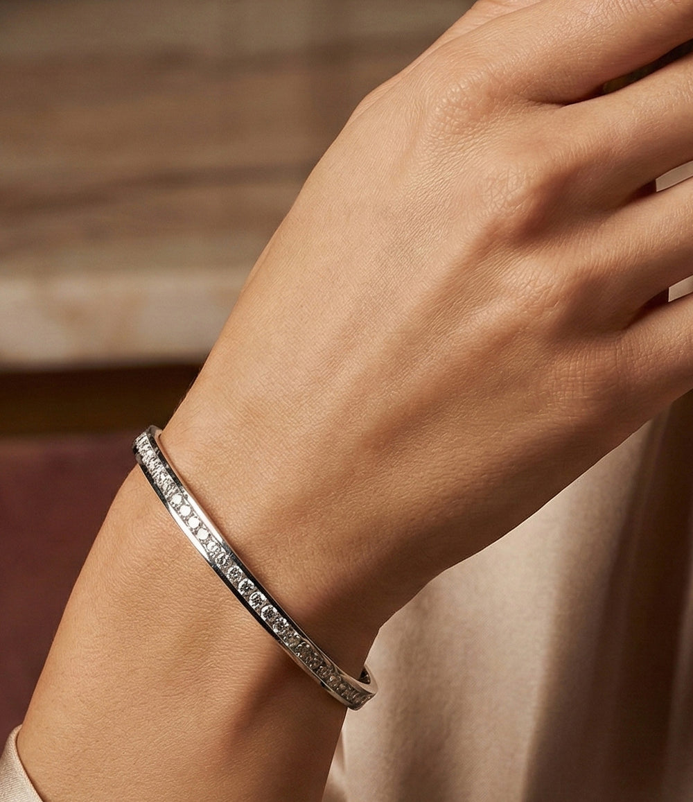 Close-up of a hand wearing a silver bracelet with a blurred background