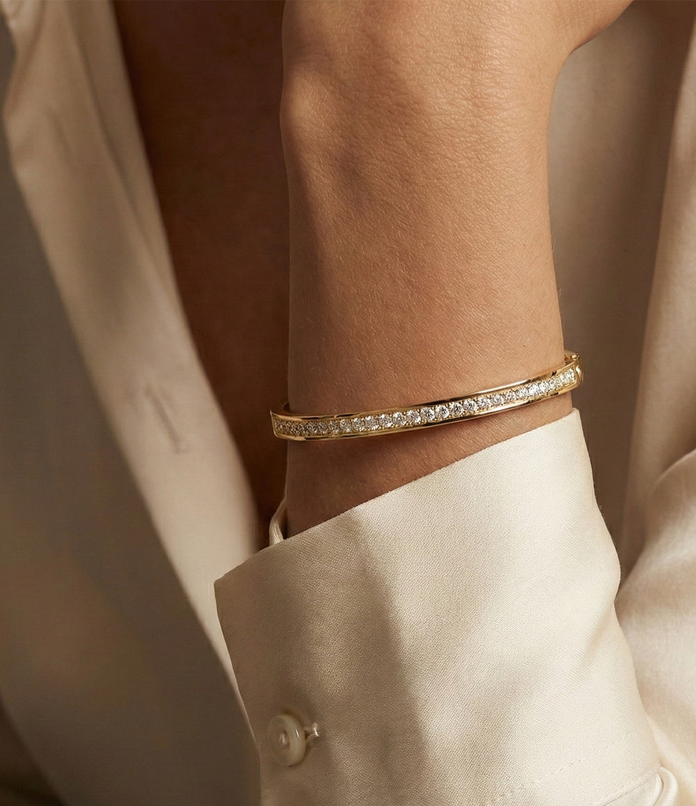 Close-up of the Duchess Bangle showing gold bangle frame with sparkling tennis-style stones on a model