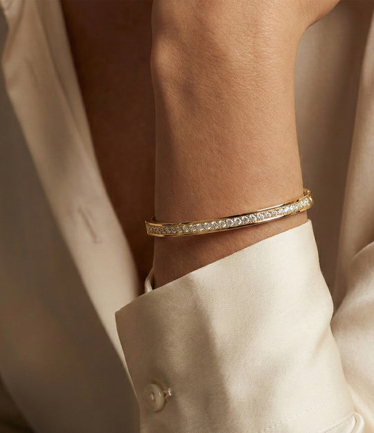 Close-up of the Duchess Bangle showing gold bangle frame with sparkling tennis-style stones on a model