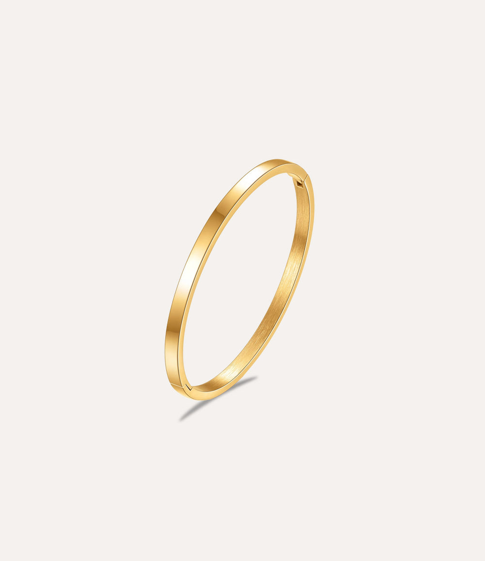 The Essential Bangle in gold titanium steel displayed on a clean white background