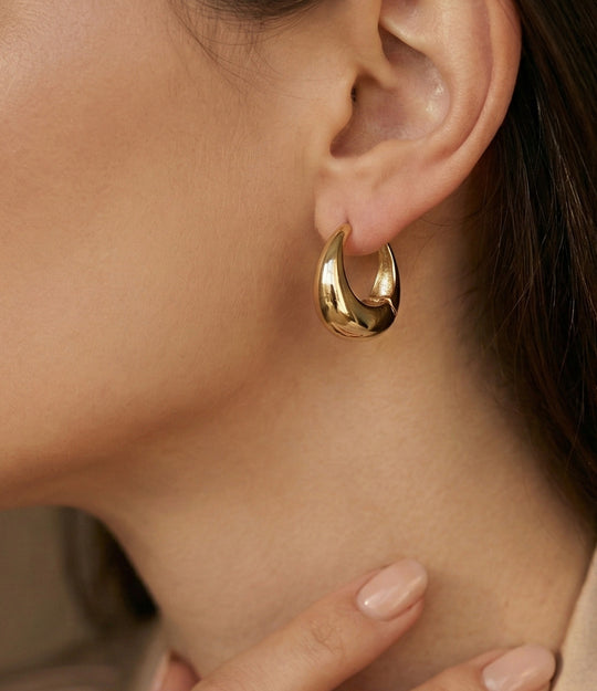 Close-up of a gold hoop earring worn by a person.