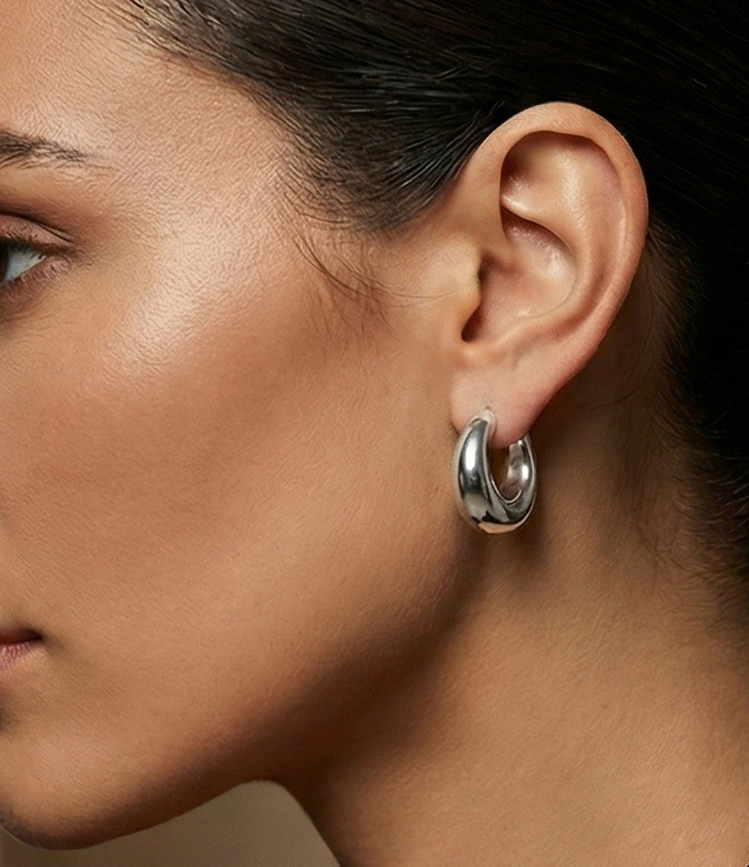 Close-up of a woman wearing a silver hoop earring.