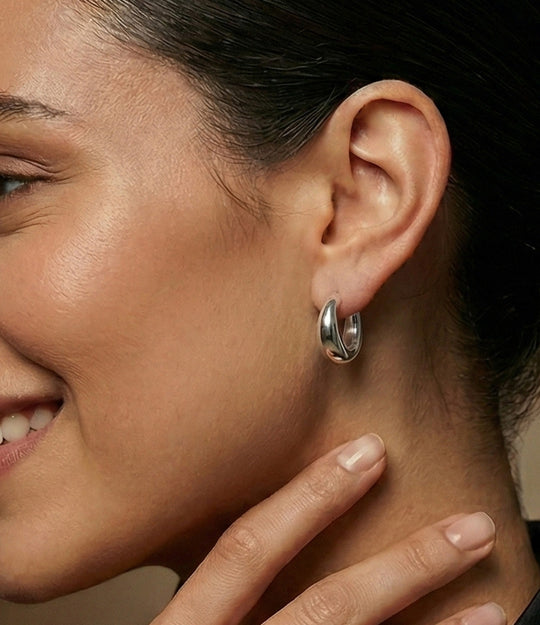Close-up of a woman wearing a silver hoop earring with a neutral background