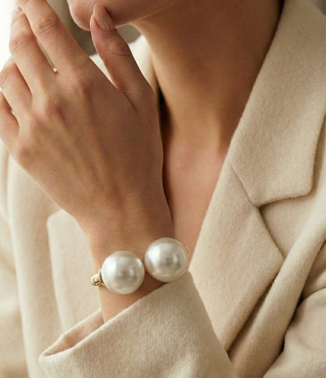 Pearl bracelet on a person wearing a beige coat