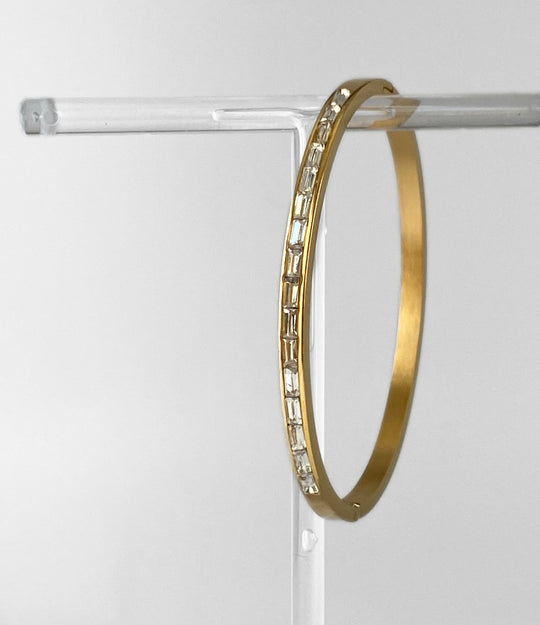 The Princess Diamond Bangle in 14K gold plated stainless steel with shimmering diamond-style stones displayed in a close-up product shot