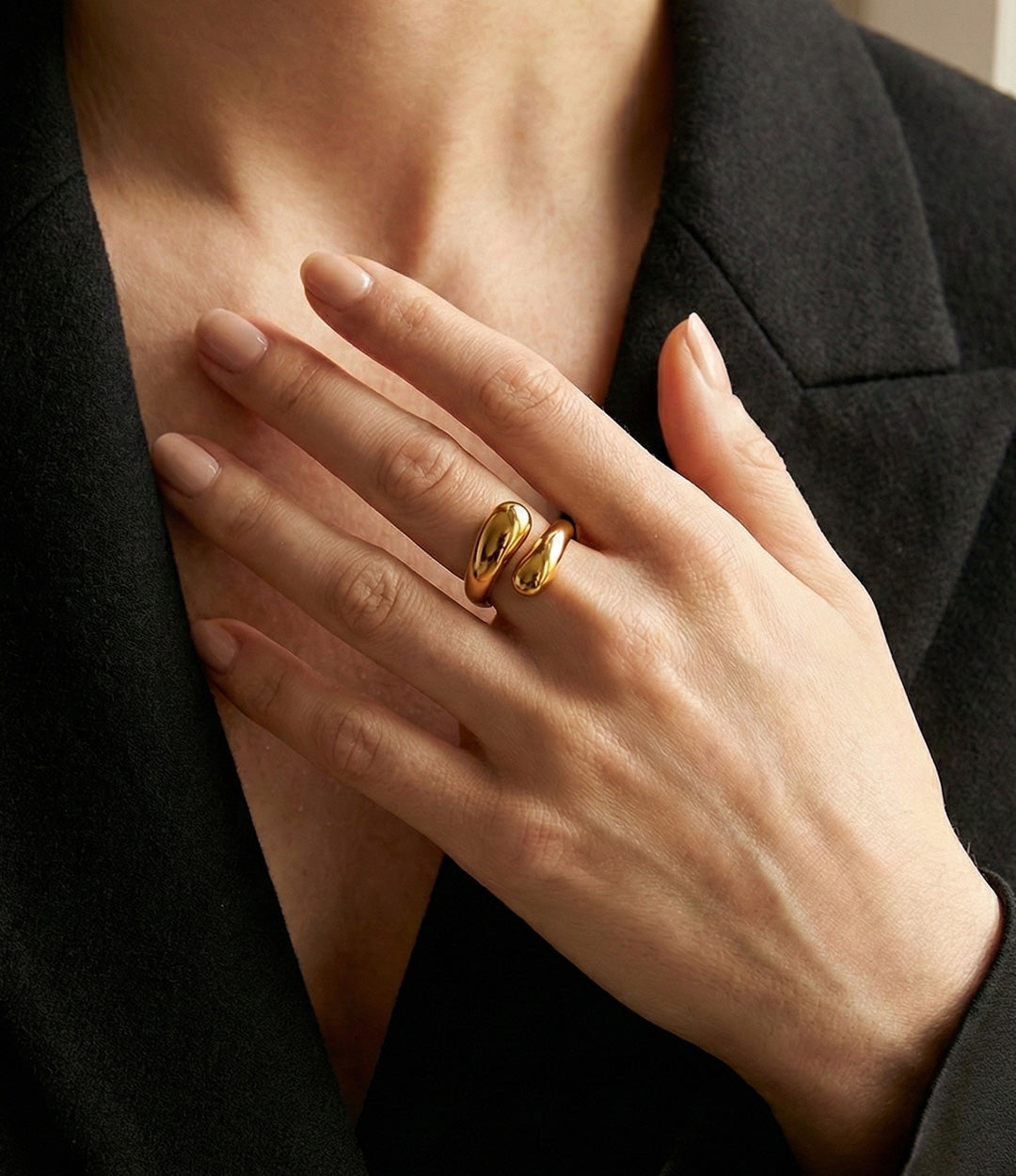 Hand wearing a gold ring with a black background