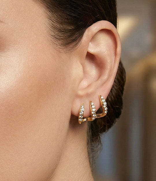 Close-up of an ear wearing two gold hoop earrings with small diamonds.